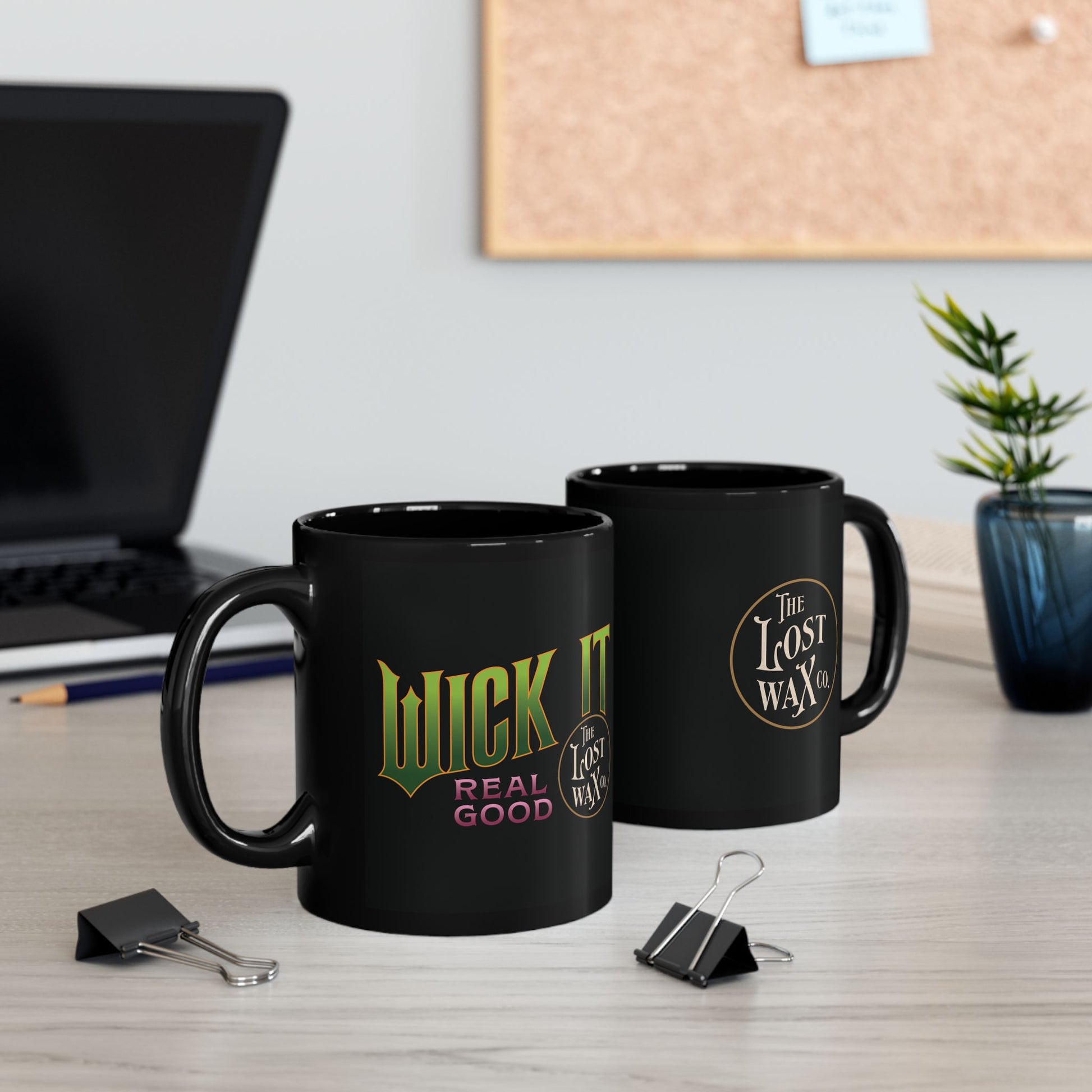 Two black mugs with branding on a desk with office supplies and decor.