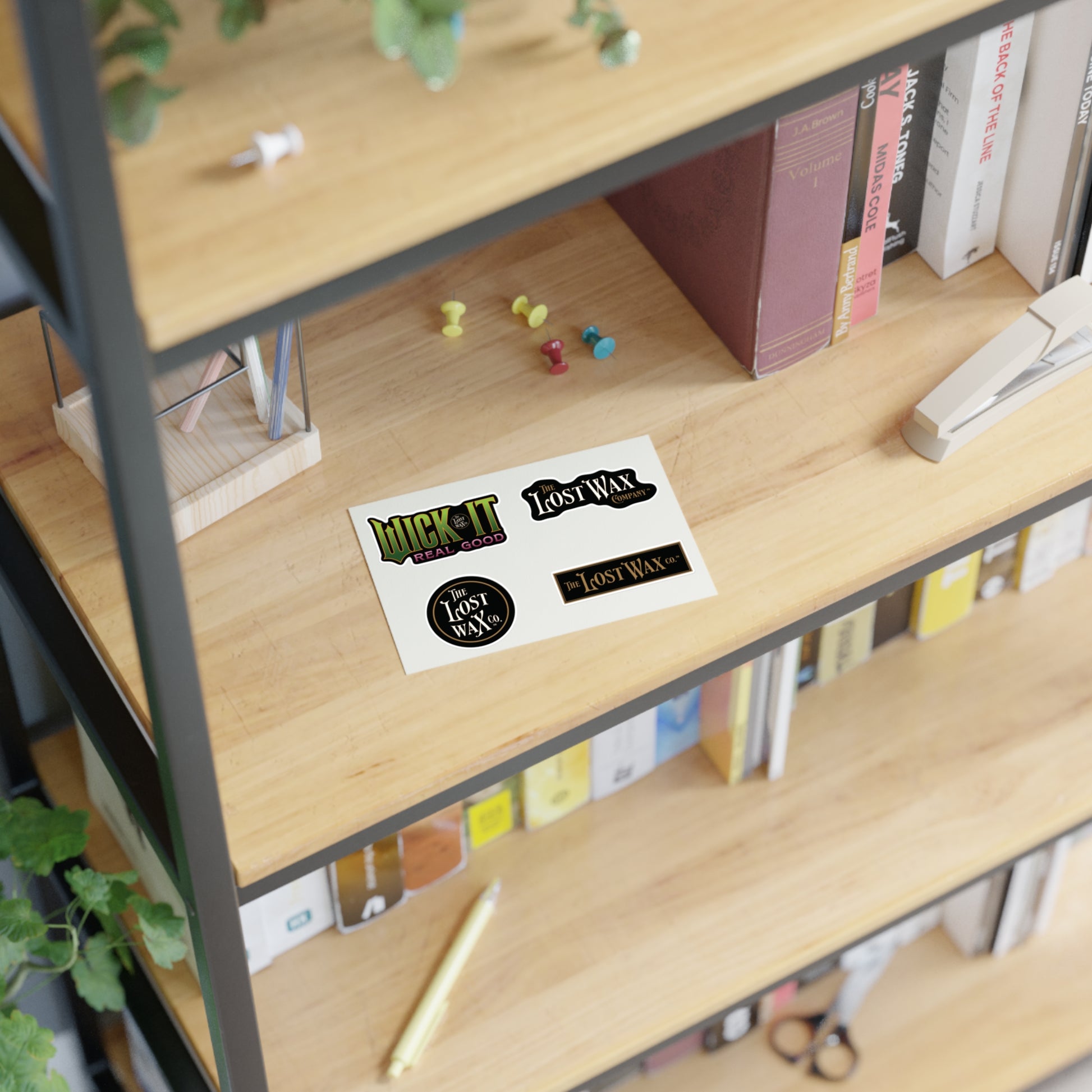 Wooden shelf with books, stationery items, and a 'Lost Wax' sticker.