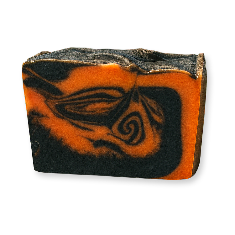A rectangular bar of handmade soap with a marbled swirl pattern of vibrant orange and black, photographed on a clean white background.