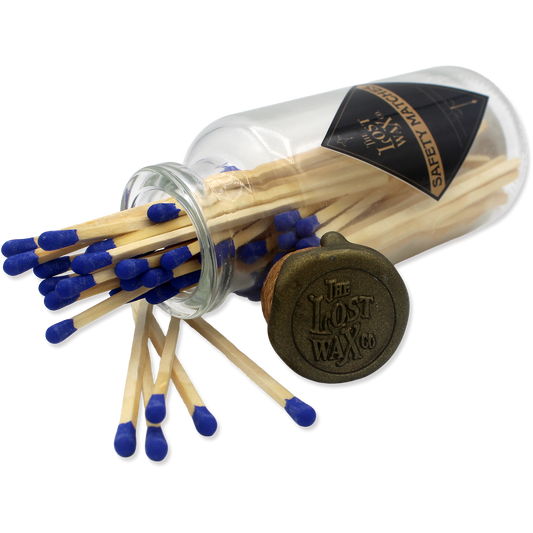 Glass jar with cork lid containing safety matches with blue tips and a visible brand label.