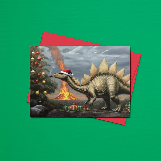 Christmas card with a dinosaur wearing a Santa hat, Christmas tree, and volcano on a green background with a red envelope.