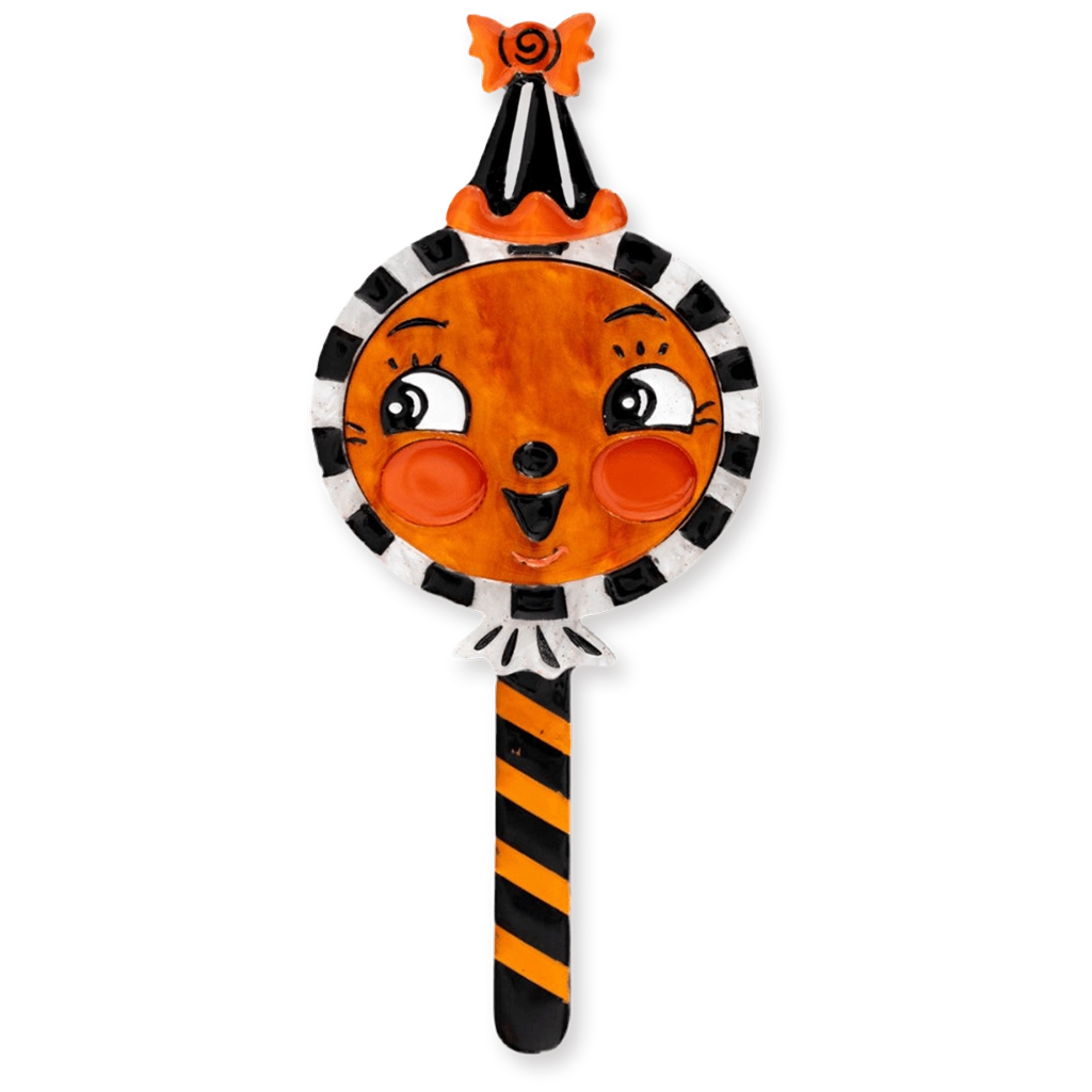 A Halloween-themed decorative candy-shaped brooch with a round orange face, black-and-white striped border, black-and-orange striped handle, and an orange-and-black pointed hat with a small black spider on top, shown on a plain white background.
