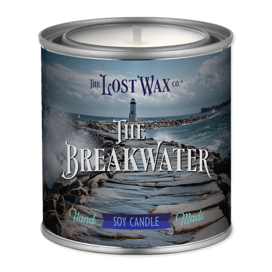 Candle in a tin labeled 'The Breakwater' from The Lost Wax Co. with a scenic design on the label.