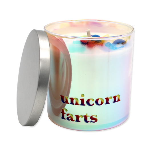 Colorful candle with fruit-shaped wax pieces in a glass container on a white background