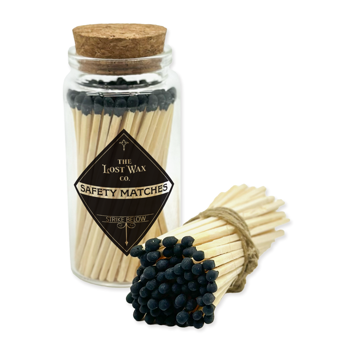 Jar of safety matches with a cork lid and a bundle of matches on a white background, featuring 'The Lost Wax Co.' branding.