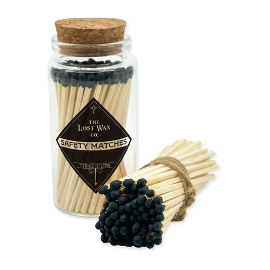 Jar of safety matches with a cork lid and a bundle of matches on a white background, featuring 'The Lost Wax Co.' branding.