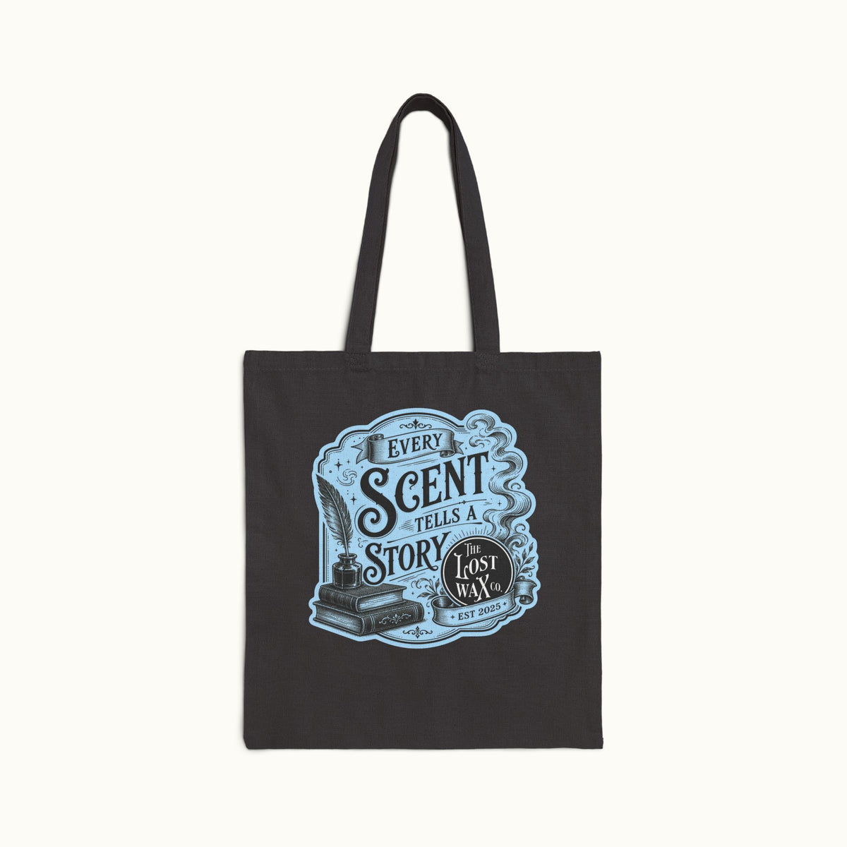 A black canvas tote bag with long handles, featuring a light blue and white vintage-style graphic on the front that reads 'EVERY SCENT TELLS A STORY' and 'The Lost Wax', shown against a plain off-white background.