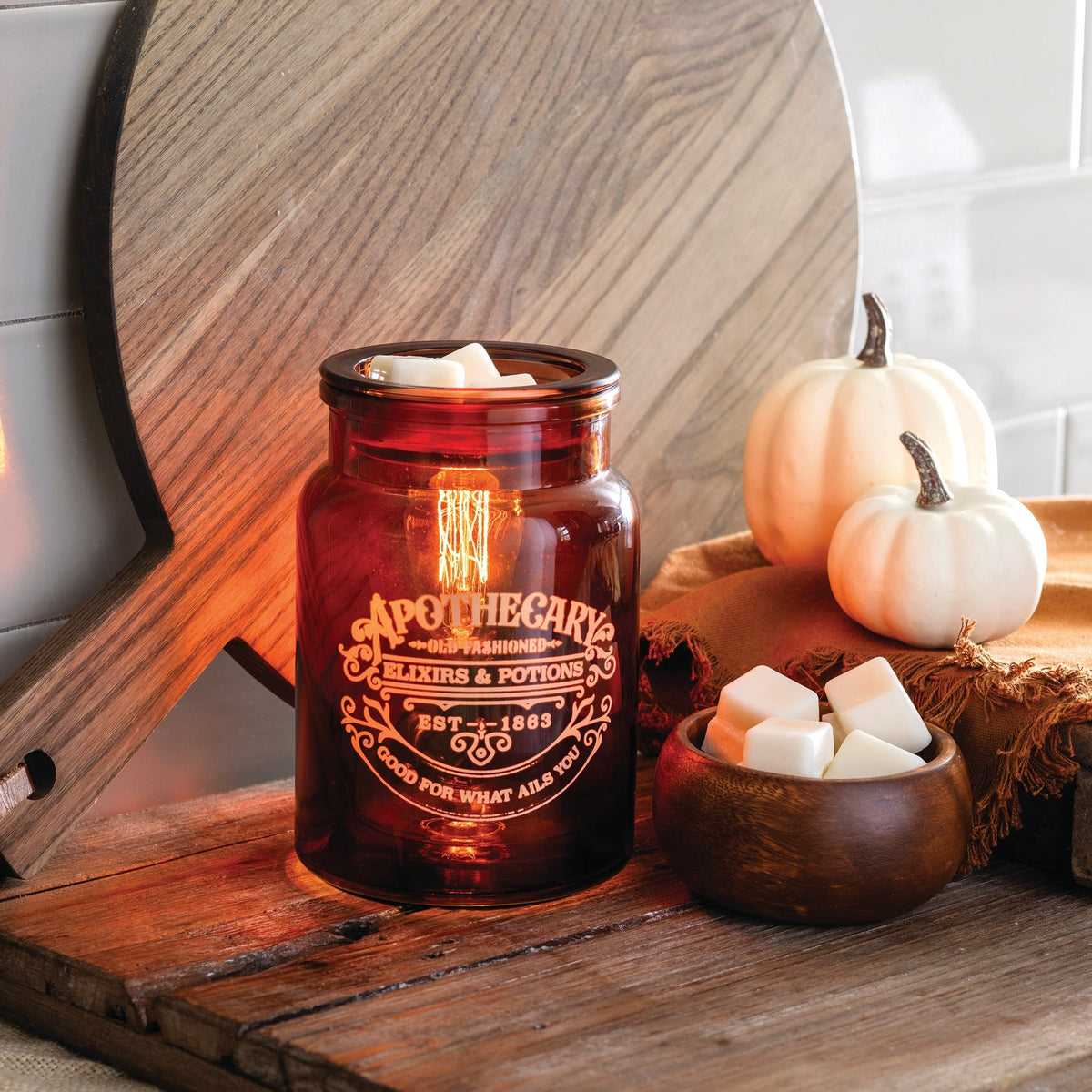 Amber glass apothecary-style jar wax warmer with Edison-style light bulb inside