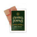Lost Wax Co. Charred Pumpkin scent wax melts in a clear plastic clamshell package with a dark green label and orange-colored wax visible behind it on a white background.
