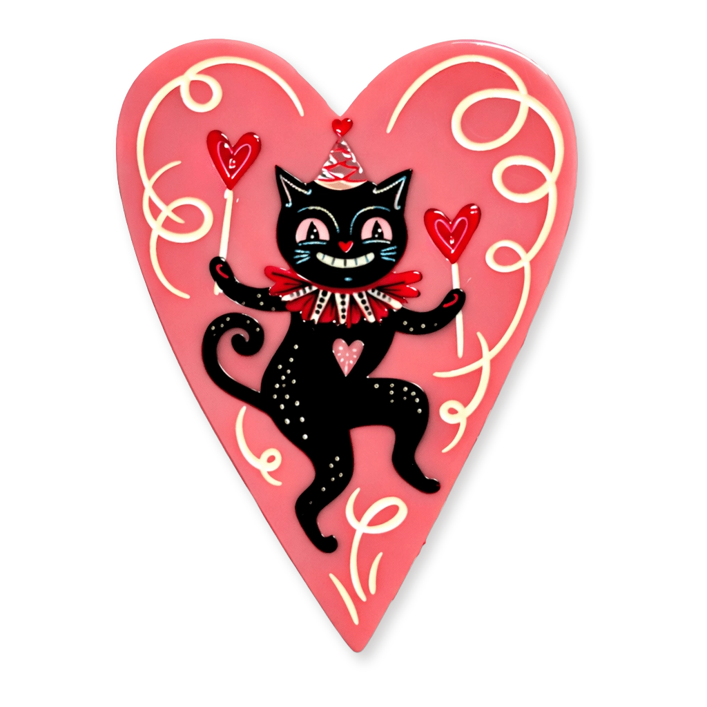 A heart-shaped decorative brooch featuring a black cartoon cat wearing a red bow tie and party hat, holding red hearts, on a pink background with cream swirl details.