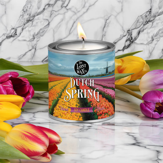Candle in a can labeled 'Dutch Spring' with tulips on a marble background