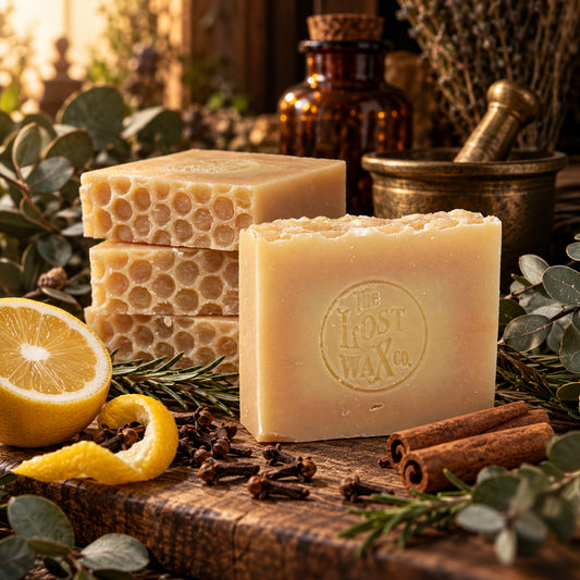 A bar of soap bearing the Lost Wax Co. brand, surrounded by a lemon, cloves, cinnamon sticks and various spices.
