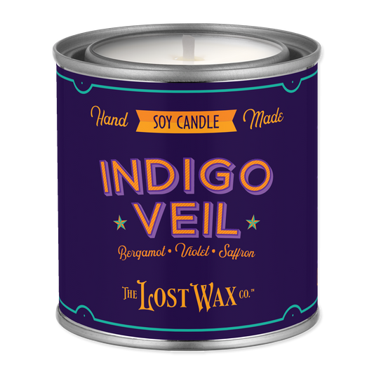 Candle in a purple canister with 'Indigo Veil' branding on a white background