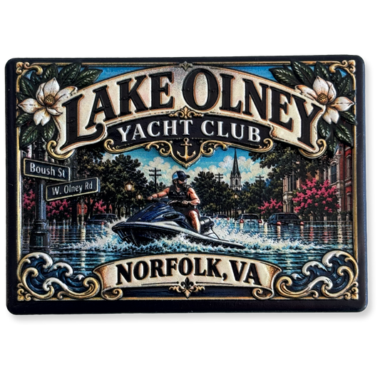 A decorative magnet featuring an illustrated scene of Lake Olney Yacht Club in Norfolk, VA. The artwork shows a person riding a jet ski through a waterfront street with flowers, buildings, street signs, and ornate blue and gold scrollwork.