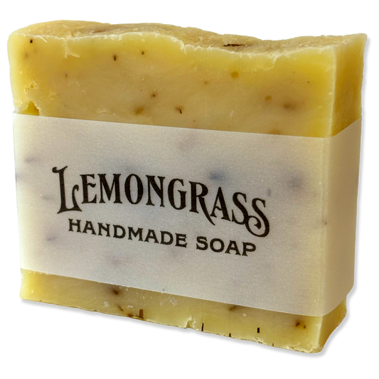A rectangular bar of Lemongrass Handmade Soap with a cream paper label, showing a pale yellow, semi-translucent texture with small dark specks, isolated on a white background.