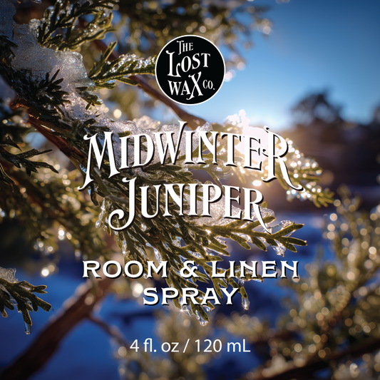Label for Midwinter Juniper room and linen spray from The Lost Wax Co. with snowy branches in the background.