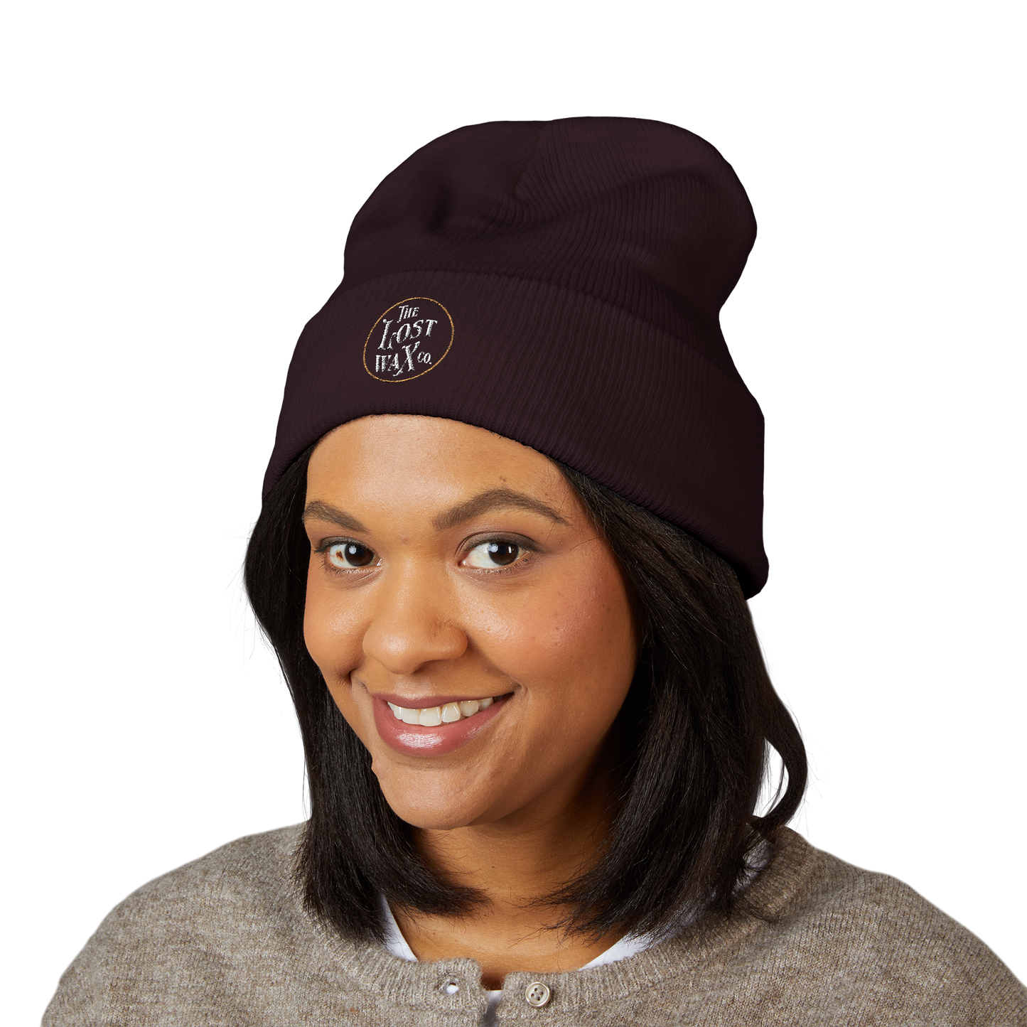 Person wearing a dark brown beanie with a logo on a white background