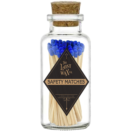 Glass jar with cork lid containing safety matches with blue tips and a visible brand label.