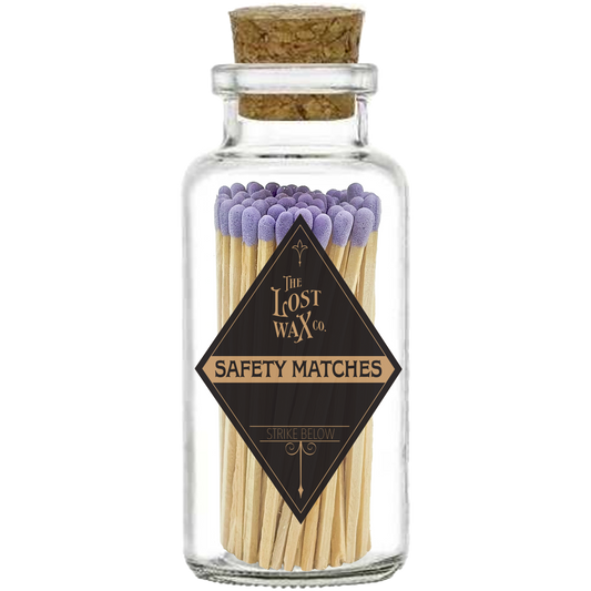 Glass jar with cork lid containing lavender-tipped safety matches branded 'The Lost Wax Co'.