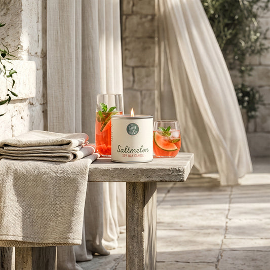Candle on a table with a stone wall and plants in the background
