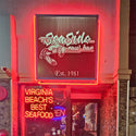 Neon sign for Sea Side Raw Bar with red neon lights on a building exterior.