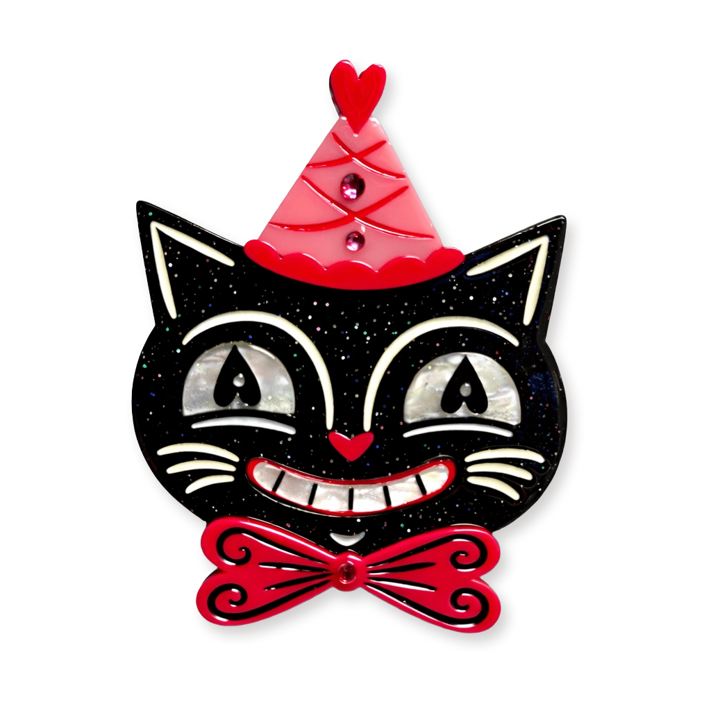 A decorative black cat face with white and silver shell-like eyes, a red party hat, and a red bow tie on a plain white background.