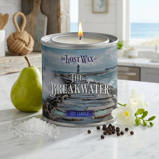 Candle in a decorative canister with 'The Lost Wax Co.' branding on a marble surface.