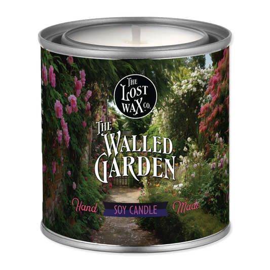 An unlit candle in a tin labeled "The Walled Garden"