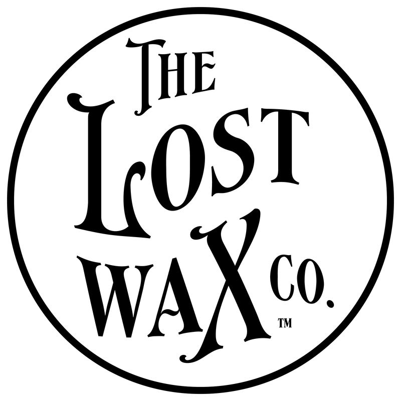 Logo of The Lost Wax Co. with a black circle on a white background