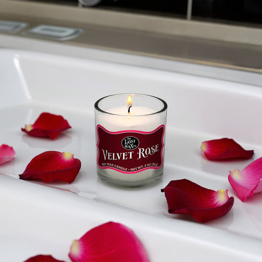 Candle labeled 'Velvet Rose' surrounded by red rose petals in a bathtub.