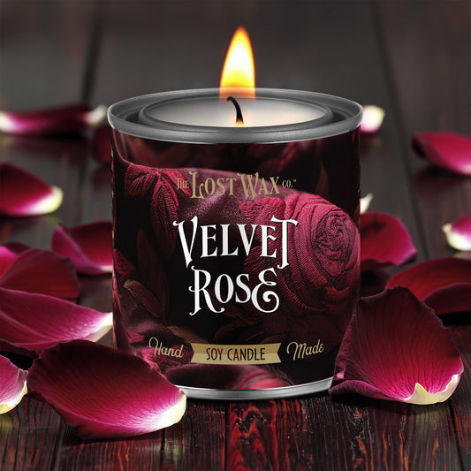 Velvet Rose candle from The Lost Wax Co. surrounded by pink rose petals on a dark surface