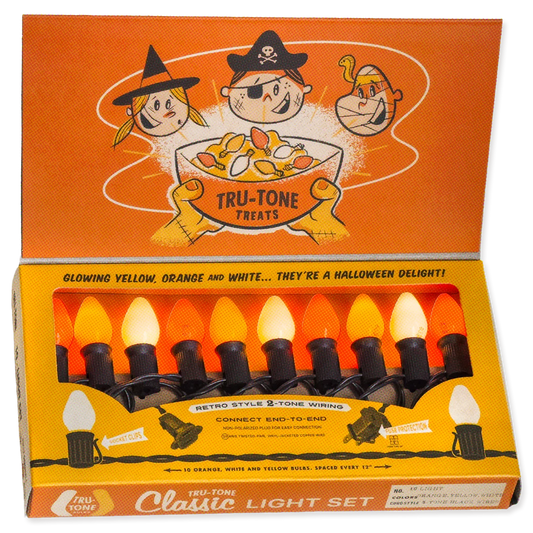 A boxed Halloween-style light set labeled Tru-Tone Classic Light Set, with an orange illustrated lid and a tray of six C7 lights in yellow, orange, and white. The packaging prominently shows Tru-Tone branding and Halloween-themed cartoon graphics.