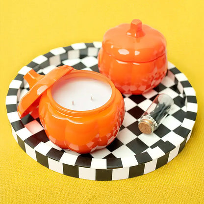Orange glass pumpkin candle holders with a checkered tray on a yellow background